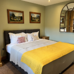 Double room with arch mirror and bed with bright yellow throw